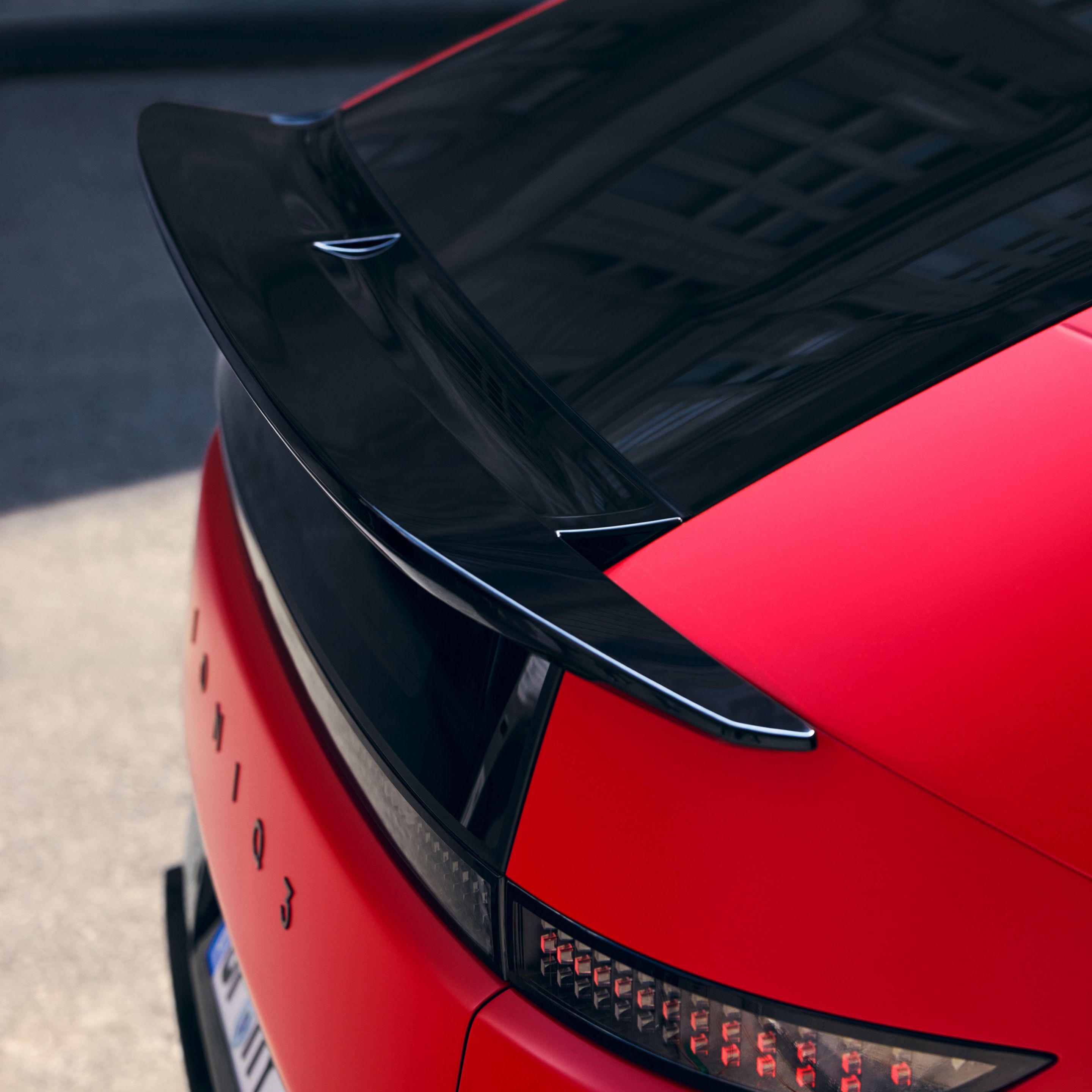 Red Hyundai IONIQ 3 rear detail with black roof spoiler and pixel-style LED taillight design.