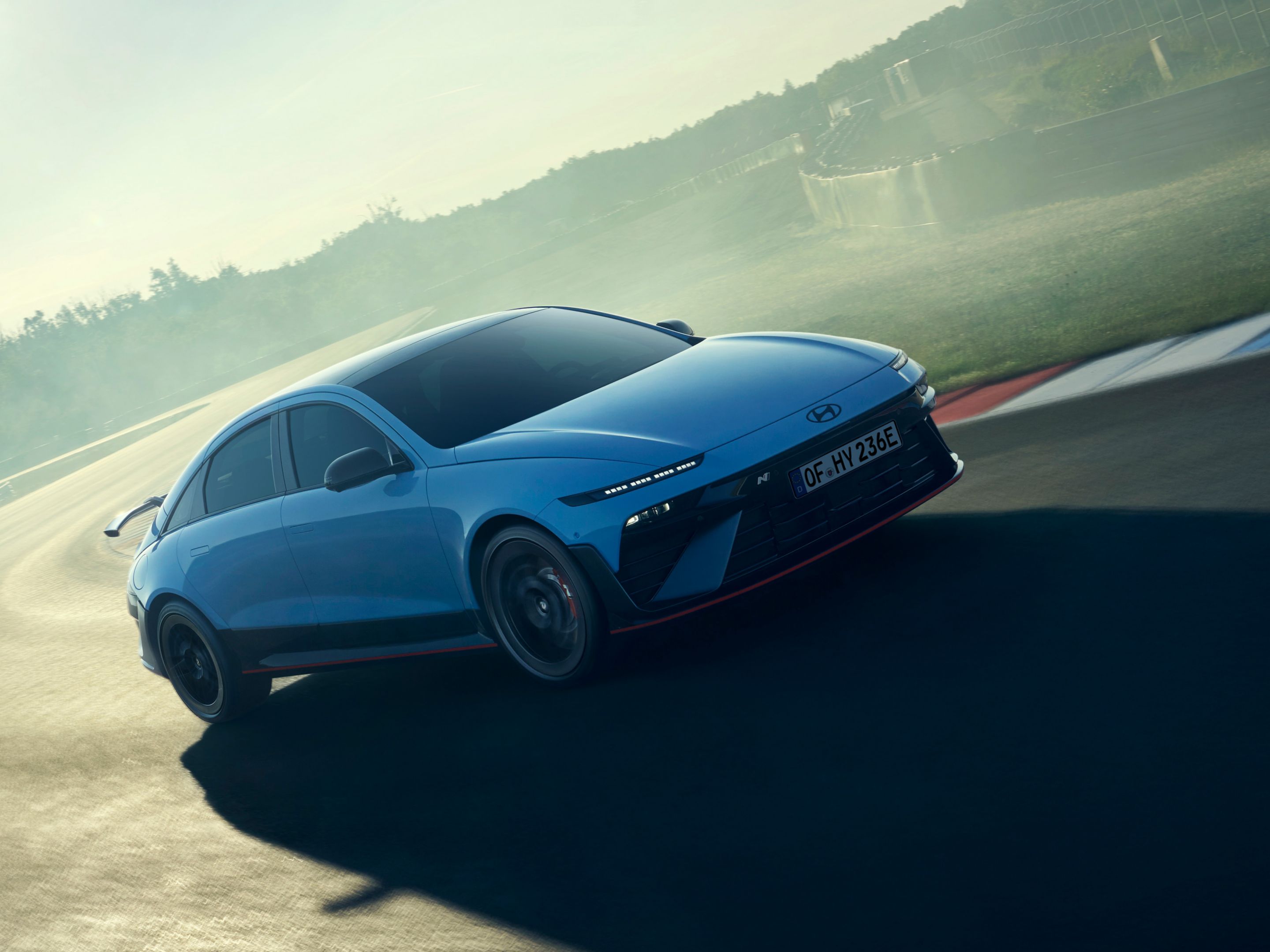 A Hyundai IONIQ 6 N versenypályán kanyarodik, a kép a jármű kecses formatervét és menetteljesítményeit szemlélteti.