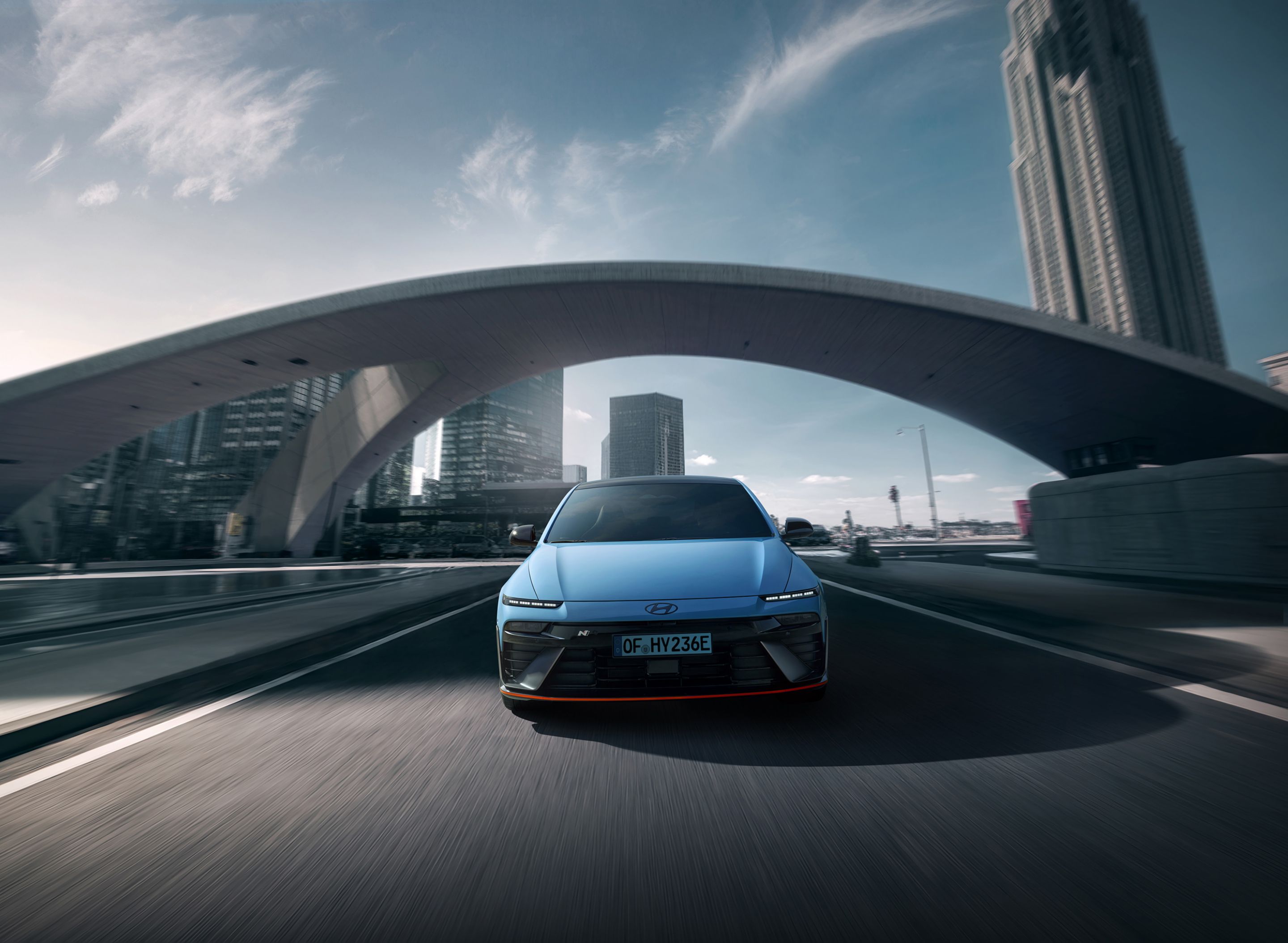 Hyundai IONIQ 6 N egy híd alatt halad, modern formatervét kiemeli a háttérben látható városi látkép.