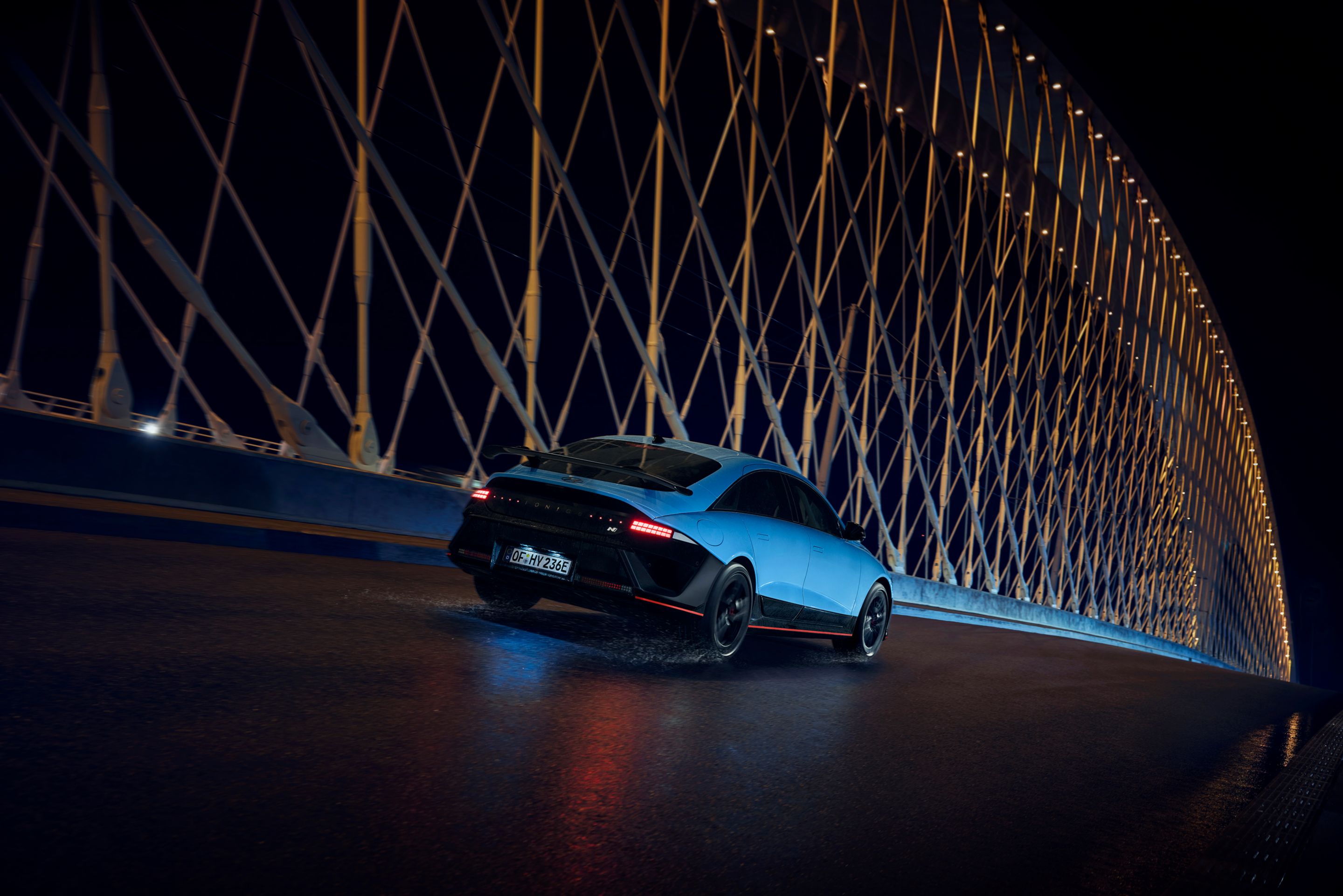 Hyundai IONIQ 6 N egy híd alatt halad el éjszaka, körülötte megvilágított építészeti elemek.