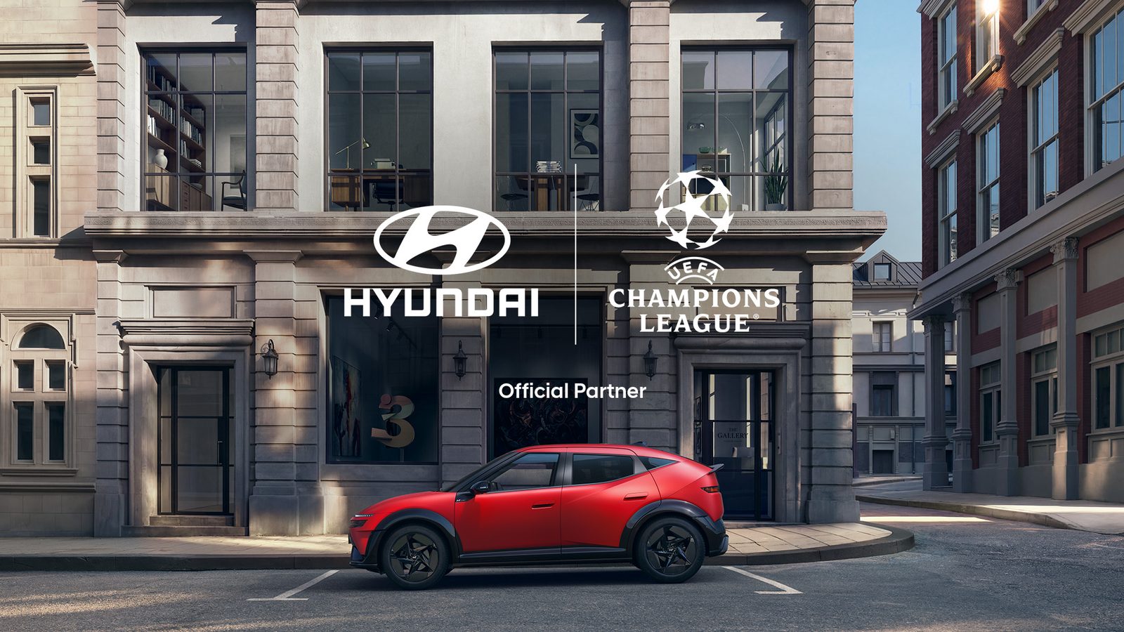 A Hyundai IONIQ 3 egy piros színű példánya a Hyundai és az UEFA-bajnokok ligája emblémák előtt parkol, a Hyundai hivatalos támogatói együttműködését szemléltetve.