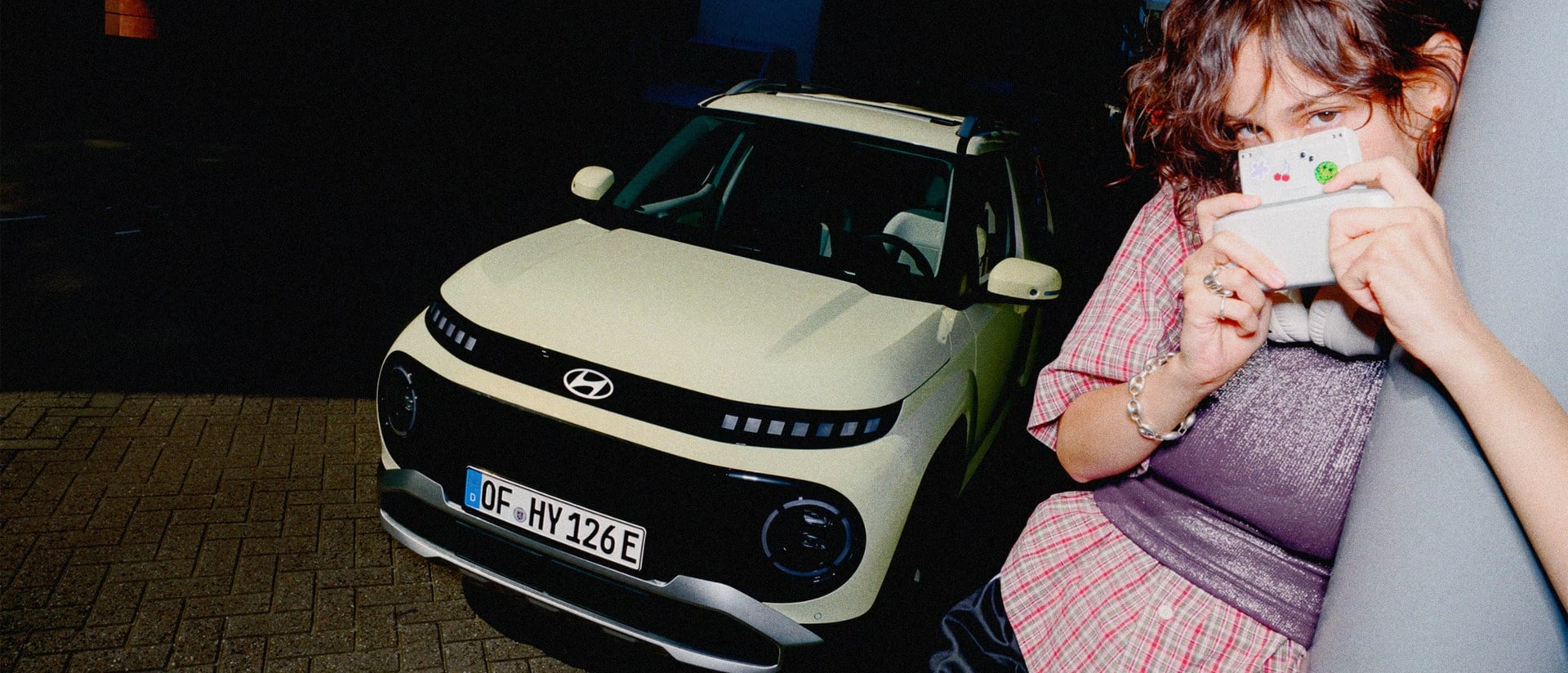 A woman standing next to the new Hyundai INSTER small electric car.