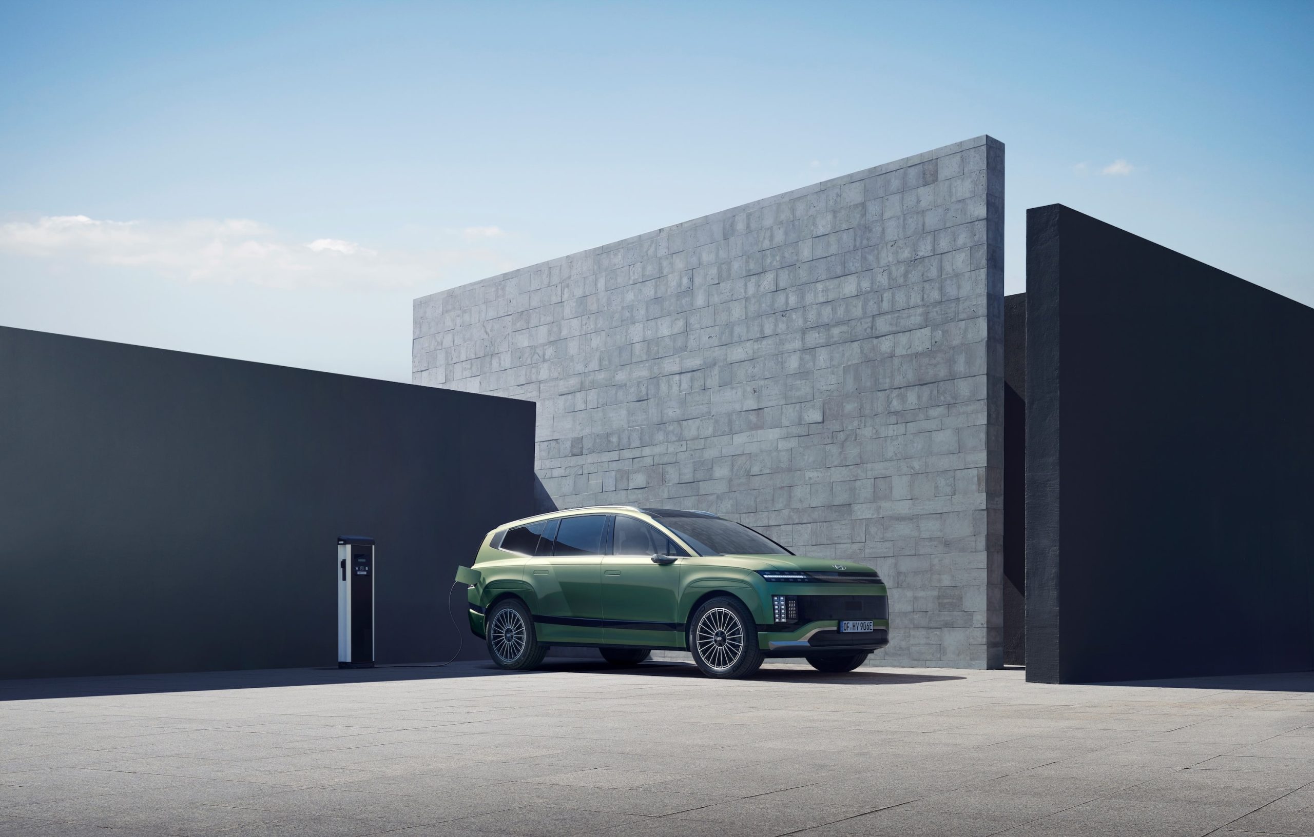 Hyundai IONIQ 9 electric SUV plugged into charge in front of a house.